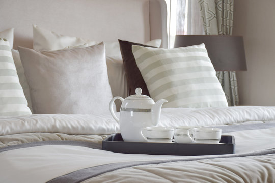 Decorative tray of tea set on the bed in modern bedroom interior