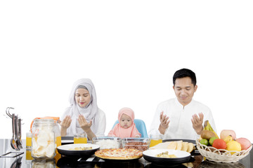 Muslim family praying before having meal