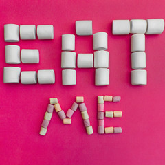Marshmallows Background with colorful marshmallows Multicolored marshmallows are lying out in the form of the inscription Eat me Pink background