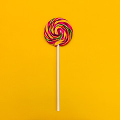 Round lollipop on a colored background Striped colorful lollipop on yellow background Minimalistic concept