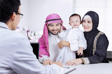 Fototapeta na wymiar Pediatrician with Arabian family in the clinic