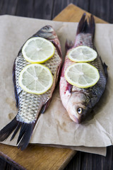 Raw fish with lemon on a cutting board. In the kitchen before cooking