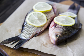 Raw fish with lemon on a cutting board. In the kitchen before cooking