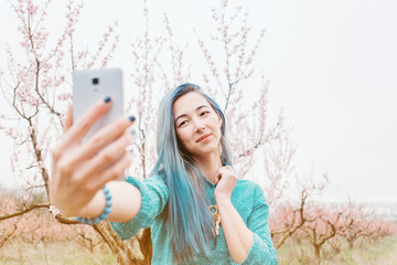 Girl taking selfie in blossoming garden.