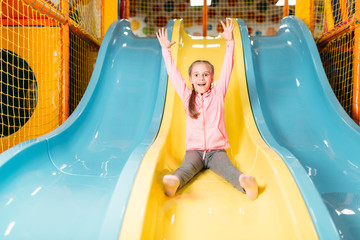Girl riding from childrens slides on playground