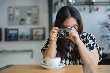woman using film camera retro hipster style in coffee shop with hot coffee / woman and camera