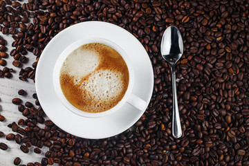 Coffee cup and metal spoon on coffee beans background. Copy space. Top view.