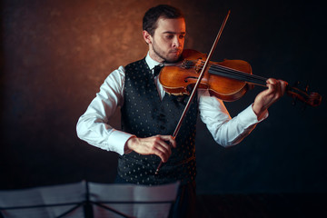 Male violinist playing classical music on violin