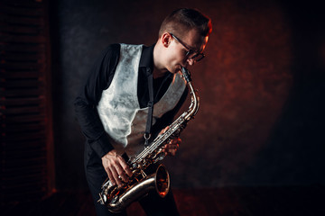 Fototapeta premium Male saxophonist playing jazz melody on saxophone