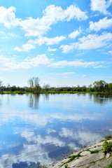Fototapeta na wymiar Rzeka i brzeg z trawą z niebem z chmurami.