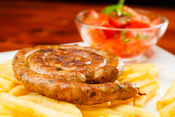 Fire grilled sausage with fries and tomato salad
