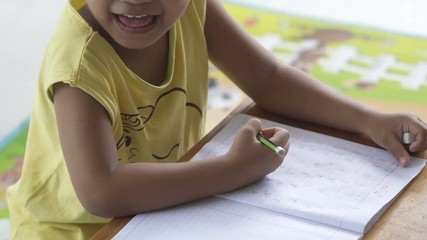 Little Asian girl doing homework by use pencil writing on notebook for writing book, uhd 4k.
