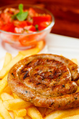 Fire grilled sausage with fries and tomato salad