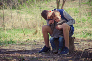 Two cute kids sitting on log in forest.