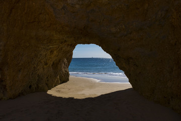 View of the Ocean from a cave in the scenic beach Praia dos Tres Irmaos in Alvor, Algarve, Portugal; Concept for travel in Portugal and Algarve