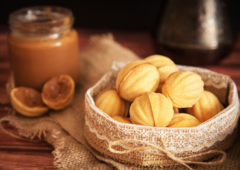 homemade cookies shaped nuts with cream boiled condensed milkt on wooden table.