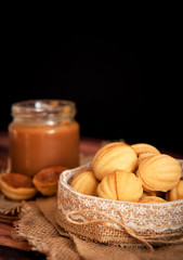 homemade cookies shaped nuts with cream boiled condensed milkt on wooden table.