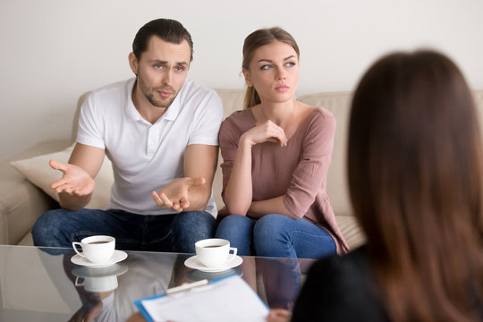 Portrait of unhappy couple talking to marriage counselor before breaking up, consulting family relationships expert, trying to save marriage. Husband speaking, his wife looking away indifferently