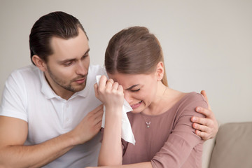 Upset crying woman wiping tears with handkerchief, loving boyfriend trying to comfort girlfriend...