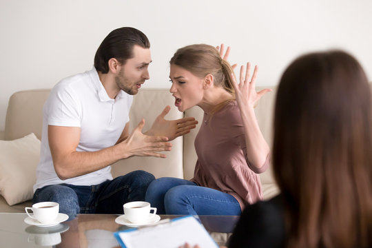 Angry aggressive couple quarrelling, screaming, shouting and blaming each other for problems while consulting family relationships expert or marriage counselor, negative emotions and hysterics