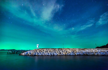 Beautiful calmness starry night sky with cloudy and colorful light at seashore pier