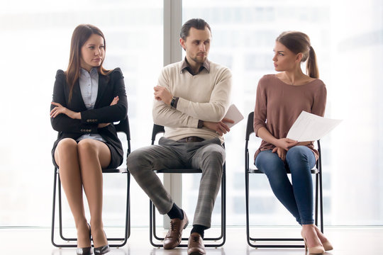 Male and female ambitious job seekers waiting for interview, looking at each other with hate and dislike, feeling jealous envious, rivalry and internal competition, get position and sidestep rivals
