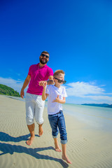 The happiest childhood: father and son running along the tropical beach