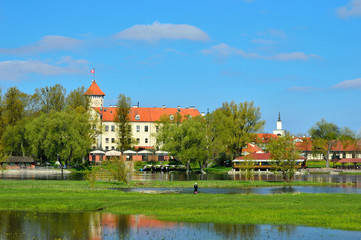 Widok na zamek w Pułtusku wśród drzew nad rzeką.