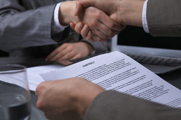Business people shaking hands after contract signing at meeting. Low key lighting.