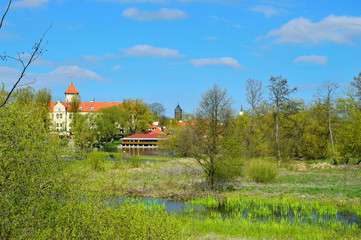 Widok na zamek w Pułtusku wśród drzew nad rzeką.