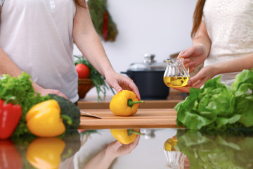 Closeup of two women are cooking in a kitchen. Friends having fun while preparing fresh salad.
