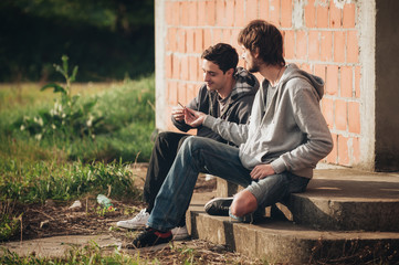 Two friends smoking joint in abandoned ghetto part of city