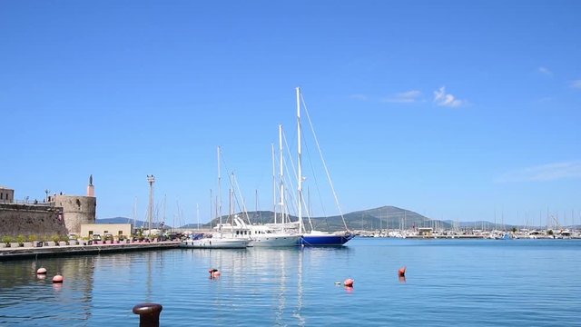 Boats in Alghero harbor on a sunny day in springtime, Italy