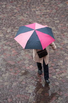 femme marchant avec un parapluie sur un place pavée