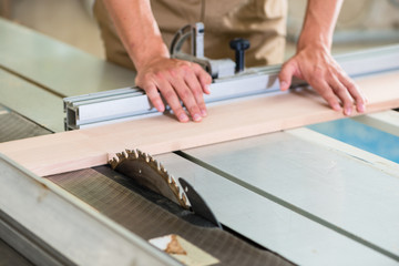 Carpenter cutting wooden board with circular saw