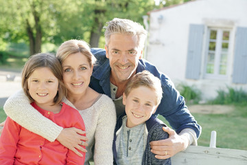 Fototapeta premium Portrait of happy family of four sitting on bench