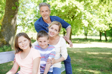Happy family sitting on bench in park