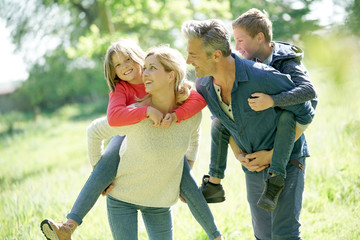 Parents giving piggyback ride to kids in countryside