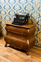 Old vintage typewriter on the wooden bureau