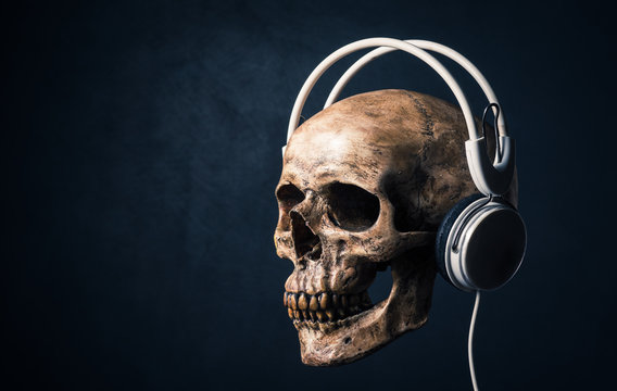 human skull listening with headphones on art dark background