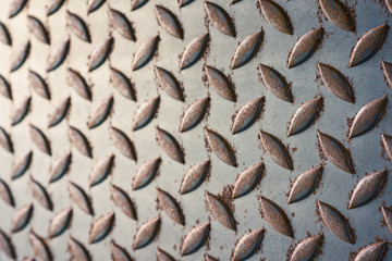 tilt angle and close up of aged metal diamond plate texture with scratch and rusty in vintage tone, selected at the right side