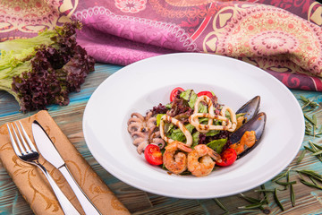 A mix of lettuce leaves with cherry tomatoes and seafood cocktail from mussels, tiger shrimps and squids