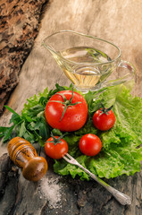 Tomatoes, salad, oil on aged wooden board.