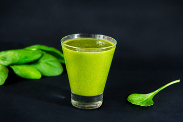 Glass of healthy green smoothie with spinach leafs on the dark background isolated. Selective focus