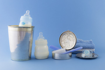 Baby boy luxurious items collection isolated on pale blue background. Milk bottle, comb, hairbrush,...