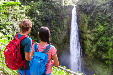 Hawaii Akaka Falls tourists at hawaiian waterfall. Young couple backpackers watching water fall on Hawaii, Big Island, USA. Travel tourism people concept.