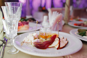 Delicious cheese plate, two kinds of cheese, Parmesan, blue, honey, carpaccio, walnut, french appetizer honey in the glass. Banquet serving at the festive table. selective focus