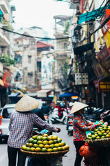 Hanoi, Vietnam - December 31, 2016: The street vendors in Hanoi, Vietnam. Woman selling fruits in the early morning on a busy street.