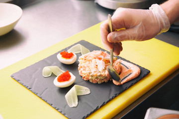 Chef is decorating crab salad in commercial kitchen, toned