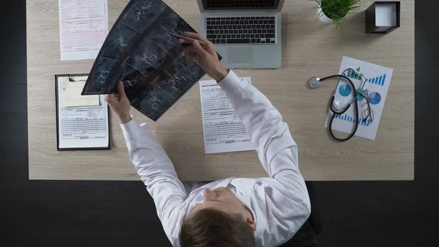 Consulting physician looking at scan of blood vessels pointing to problem places
